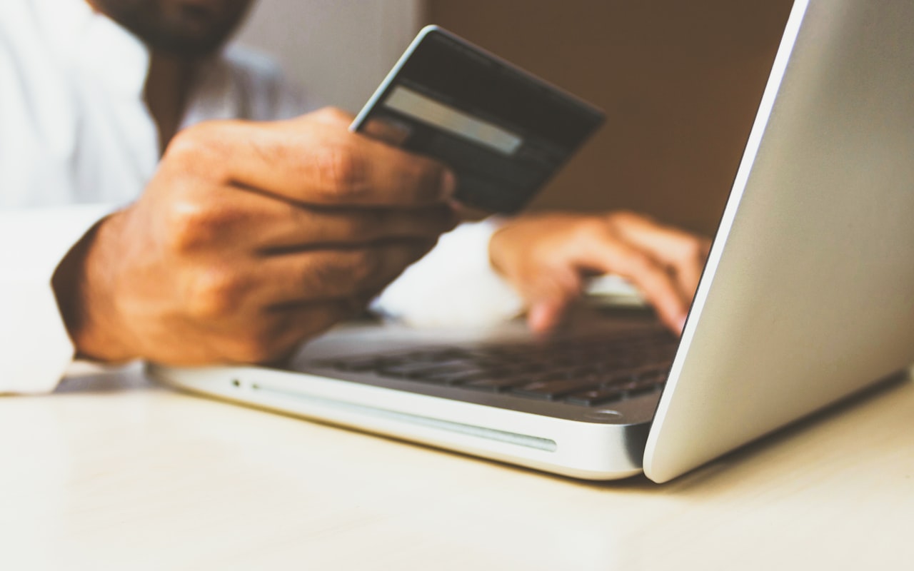 Shopper browsing an online clothing store on a phone while holding a credit card